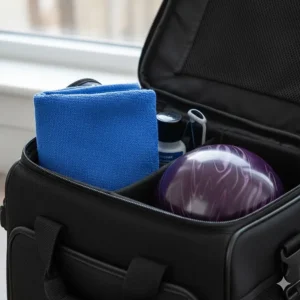 A folded bowling ball towel neatly tucked into a bowling bag compartment next to the bowling ball, showing storage.