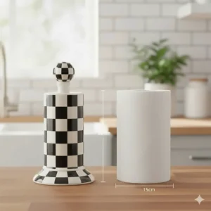 A side-by-side comparison illustrating the standard size of the Mackenzie-Childs paper towel holder next to a roll of paper towels.