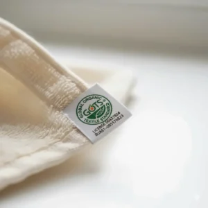 A close-up of a GOTS certified organic label on a white cotton towel hem, ensuring eco-friendly production standards.